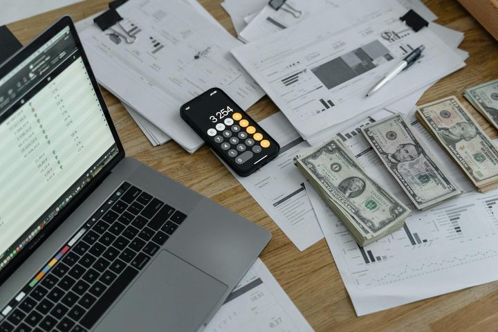 A laptop, calculator and financial documents on a desk for budgeting