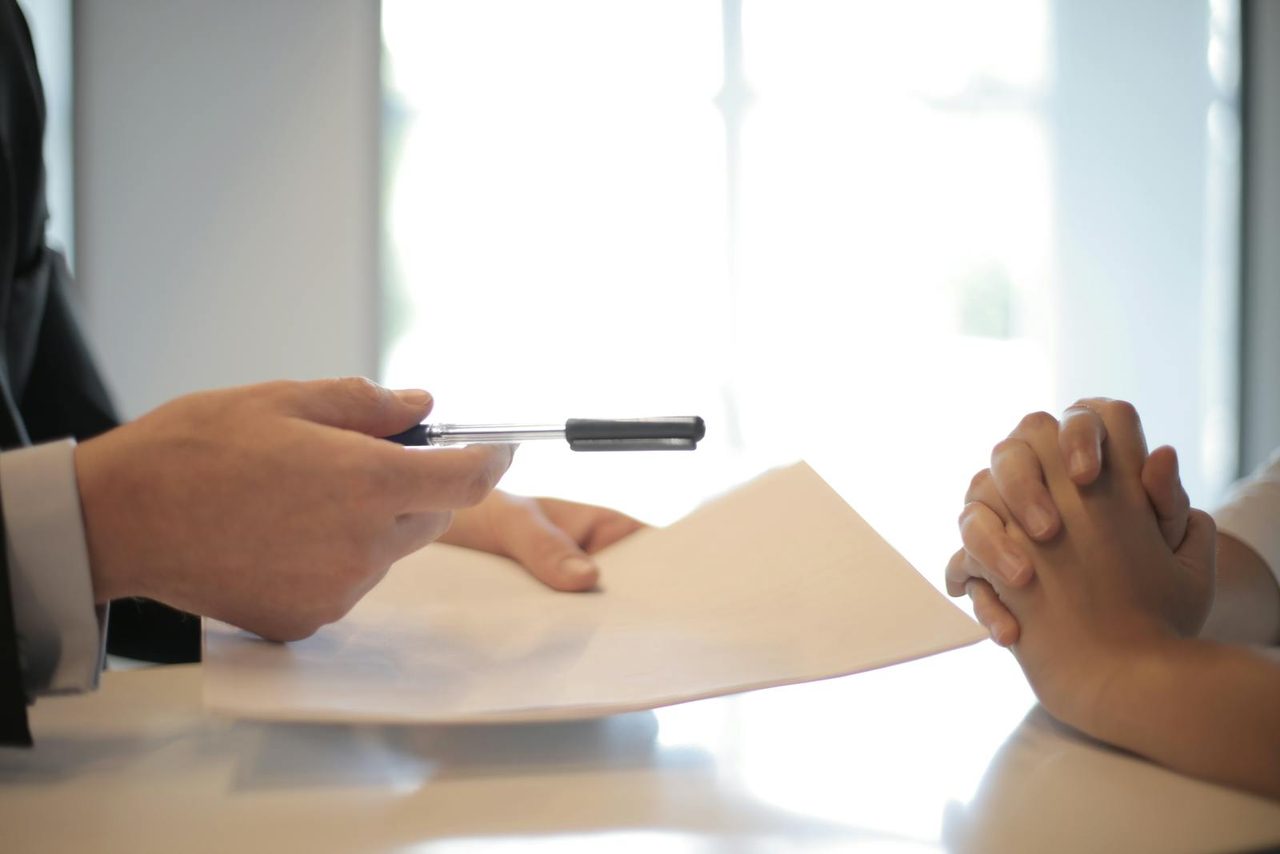 A person signing paperwork at a desk to start reporting rent payments